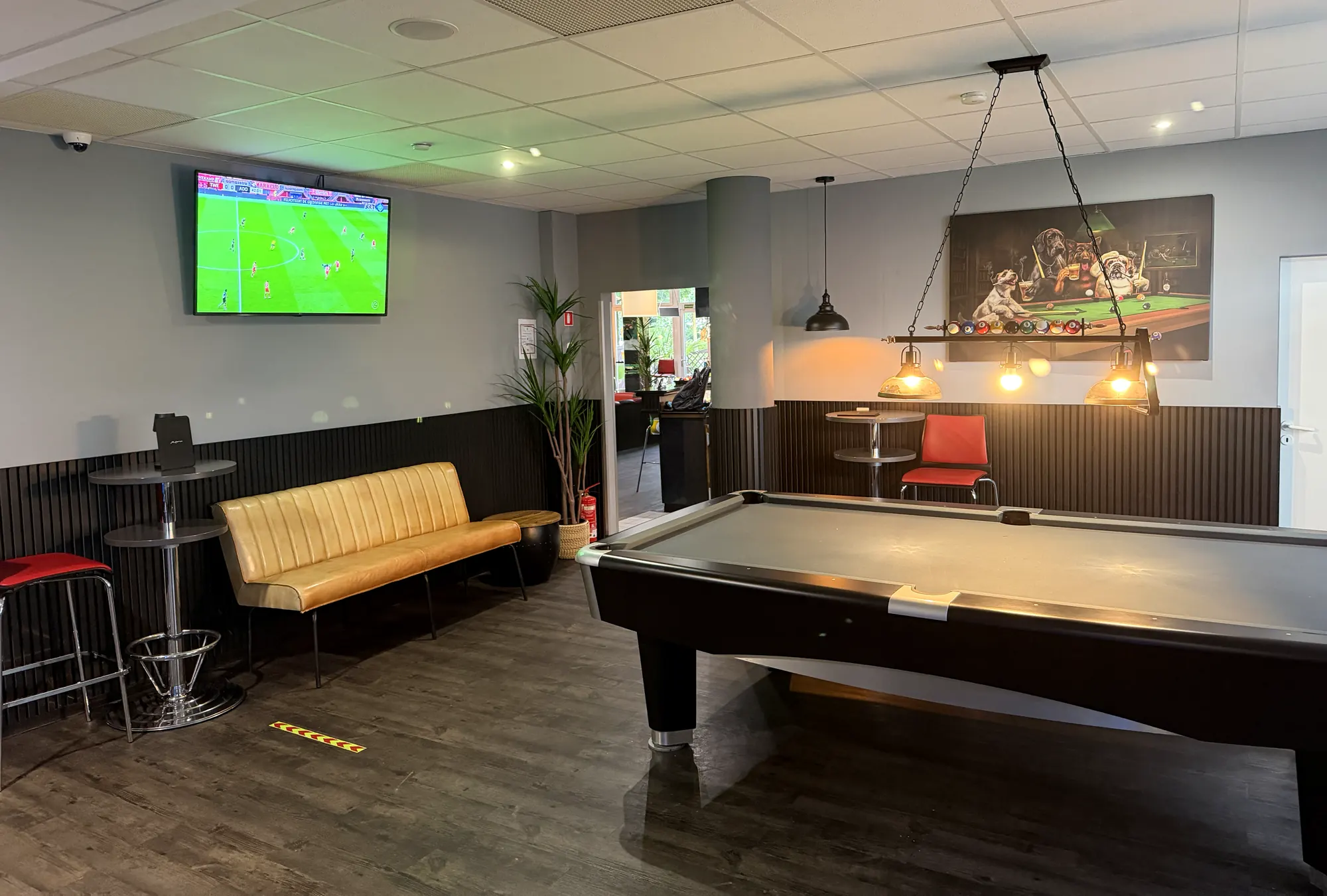 Nebenraum der Players Lounge mit Billardtisch, Sofa und Bildschirm